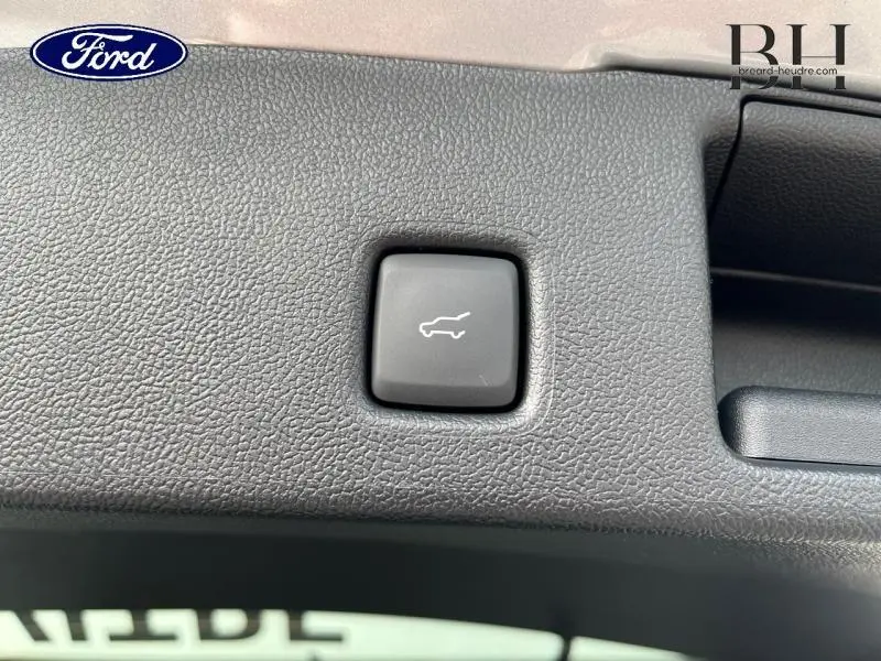 Gros plan sur le bouton d'ouverture électrique du coffre dans l'habitacle du Ford Kuga gris Solar Métallisée.