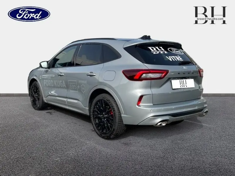 Vue 3/4 arrière droite du Ford Kuga gris Solar métallisé avec jantes noires et double sortie d’échappement chromée.