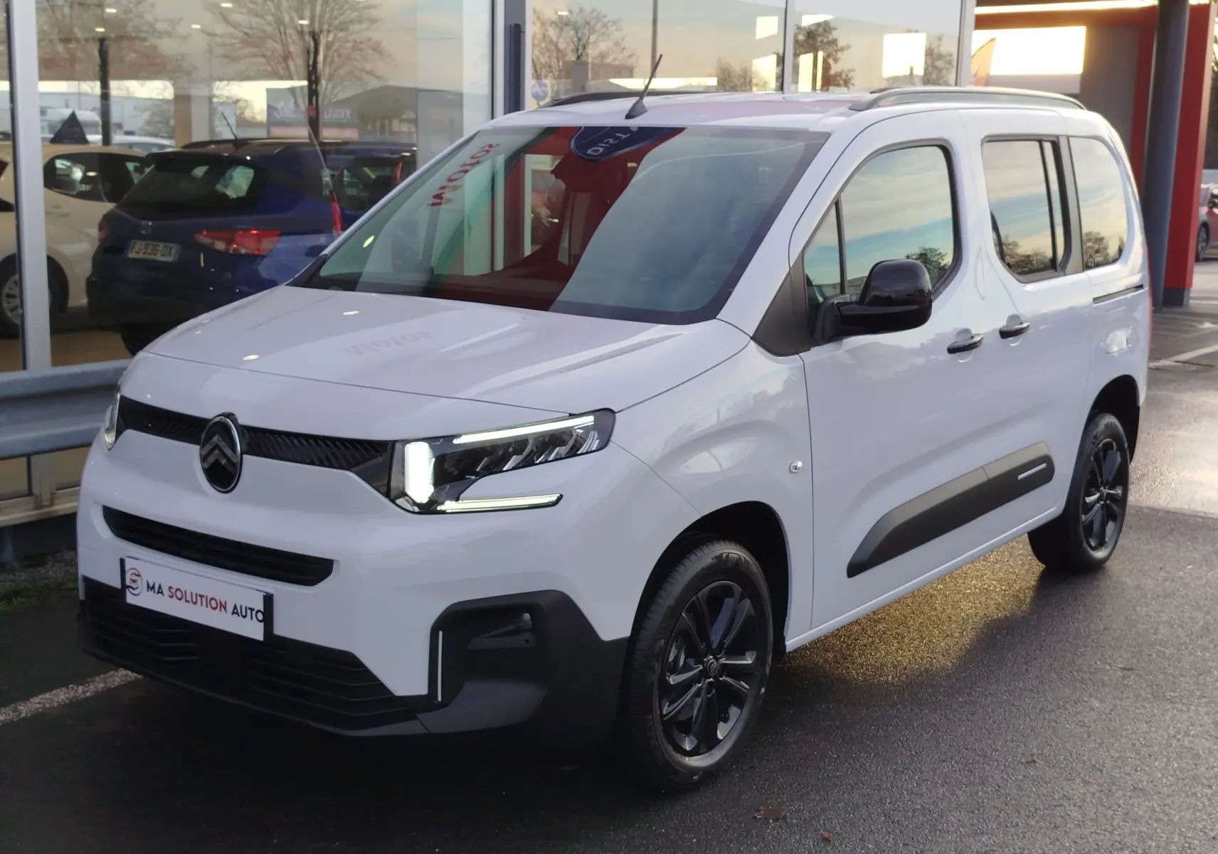 Vue 3/4 avant droite d'un Citroën Berlingo blanc Kaolin avec détails noirs et jantes noires brillantes.