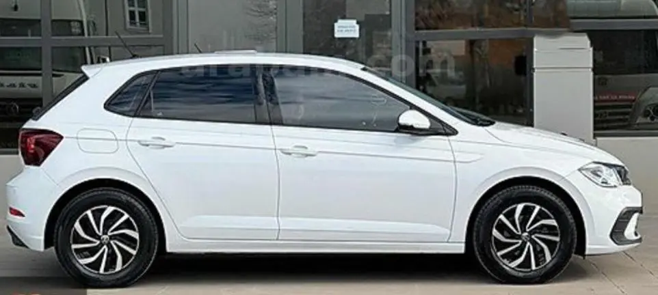 Vue de profil côté gauche d'une Volkswagen Polo blanche 2023 avec jantes noires et détails modernes.