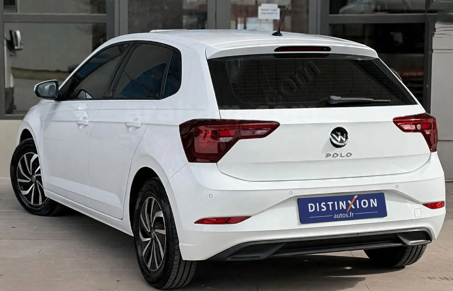 Vue 3/4 arrière gauche d'une Volkswagen Polo blanche 2023 avec feux arrière LED et jantes alliage noires.
