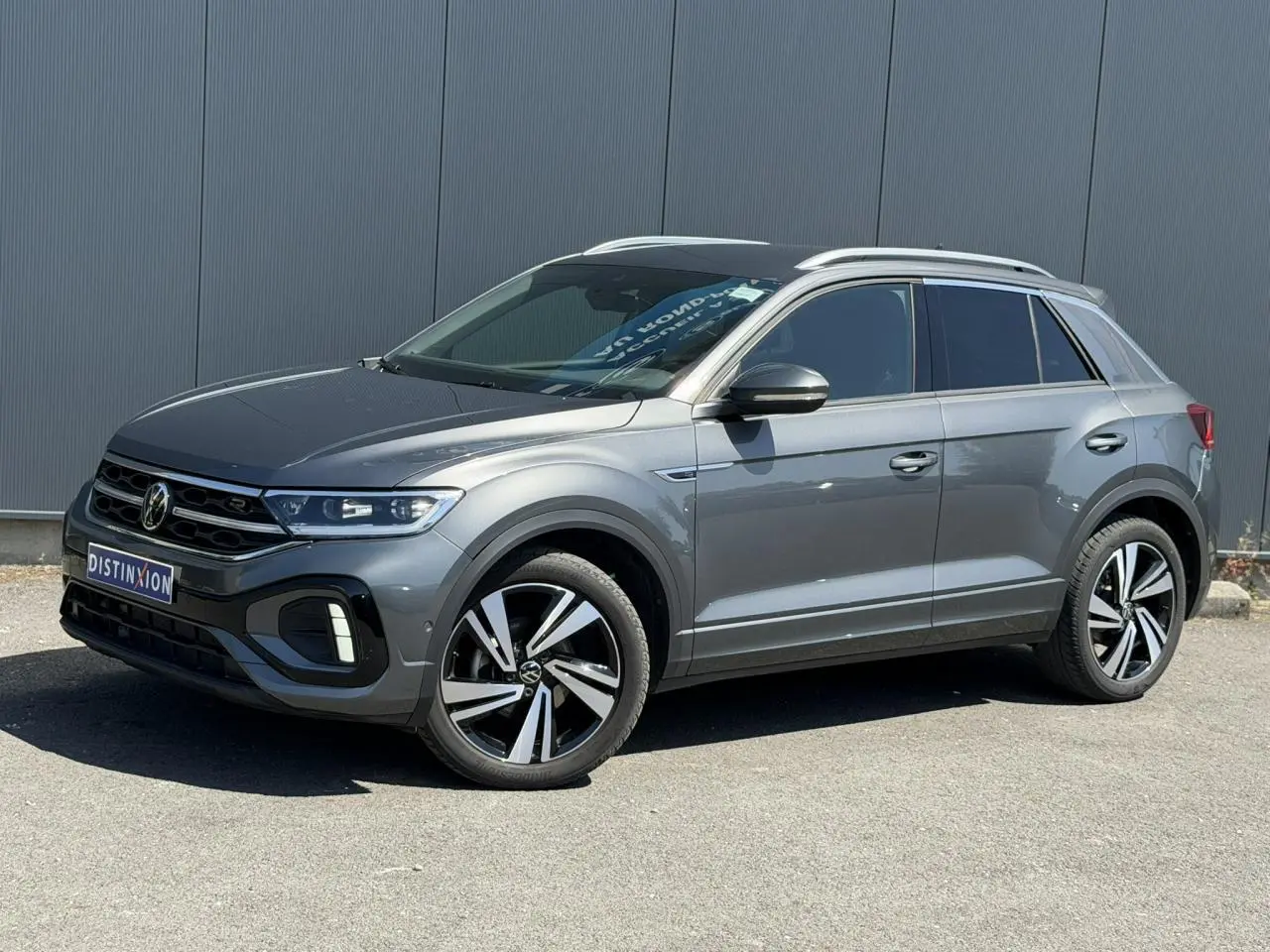 Volkswagen T-Roc gris Indium en 3/4 avant droit, avec jantes alliage 18" Nevada et logo R-Line sur calandre.