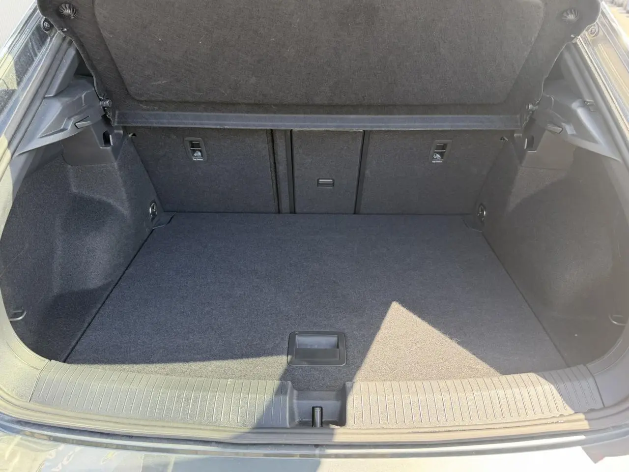 Coffre ouvert vu de l'arrière d'un Volkswagen T-Roc gris Indium, espace de chargement propre et spacieux.