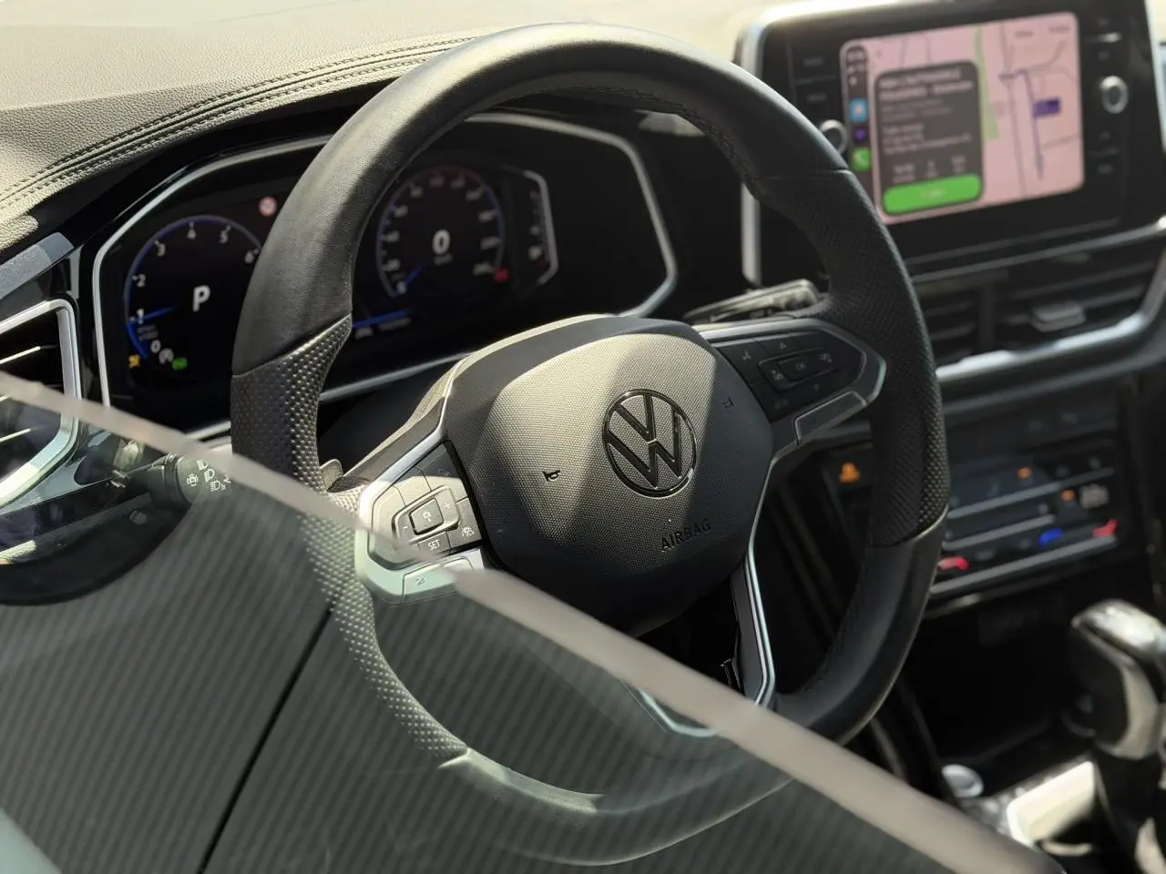 Vue rapprochée du volant noir multifonction Volkswagen T-Roc 2025 avec tableau de bord digital et écran tactile.