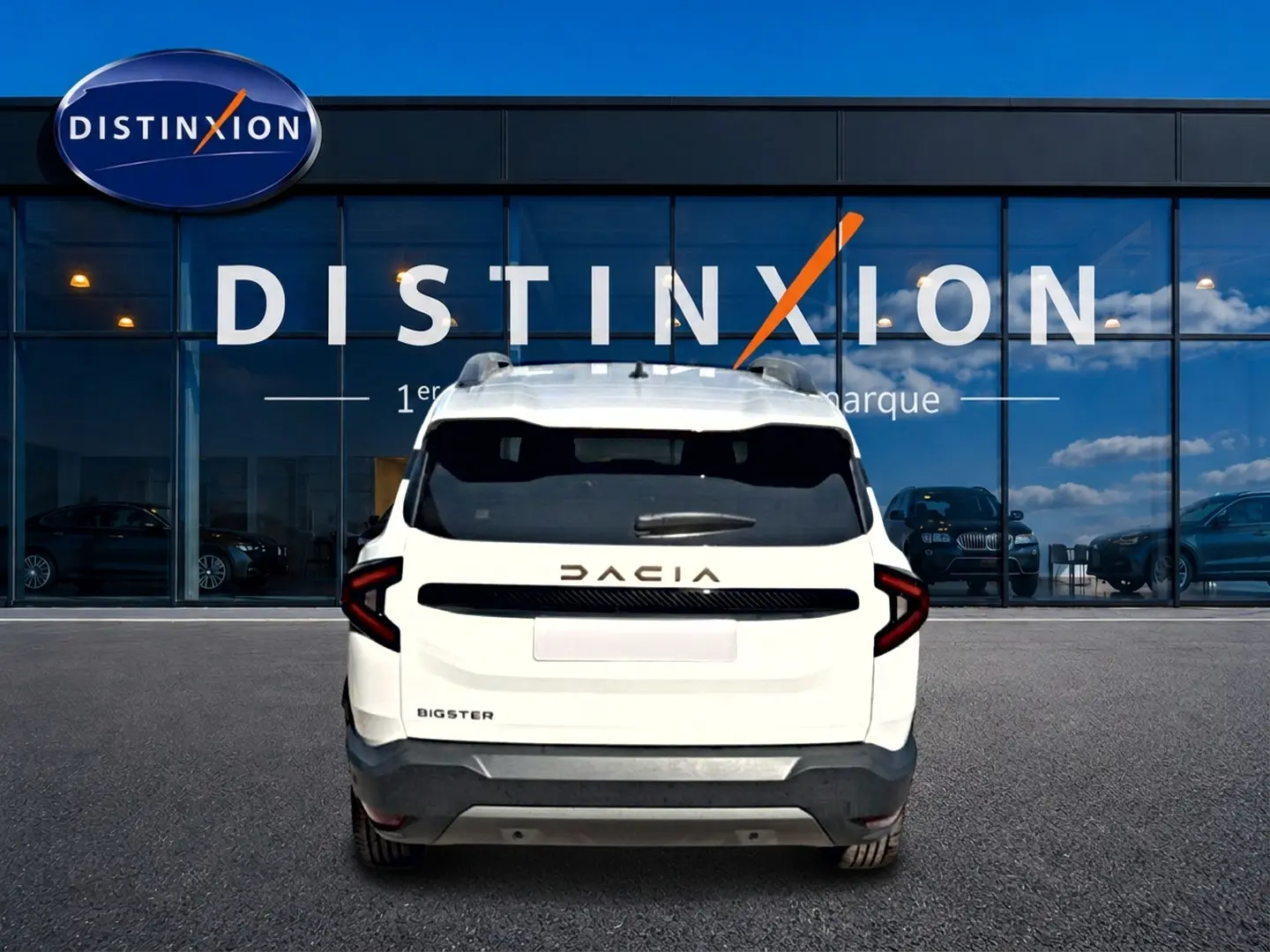 Vue arrière d'un Dacia Bigster blanc avec barres de toit et logo DACIA en relief sur fond de vitrine Distinxion.