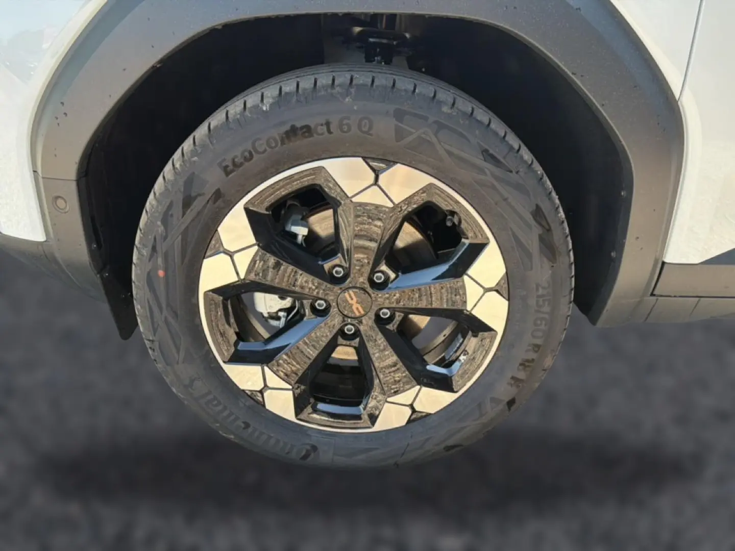 Gros plan sur la roue avant droite du Dacia Bigster blanc, mettant en valeur la jante alu bicolore au design moderne.