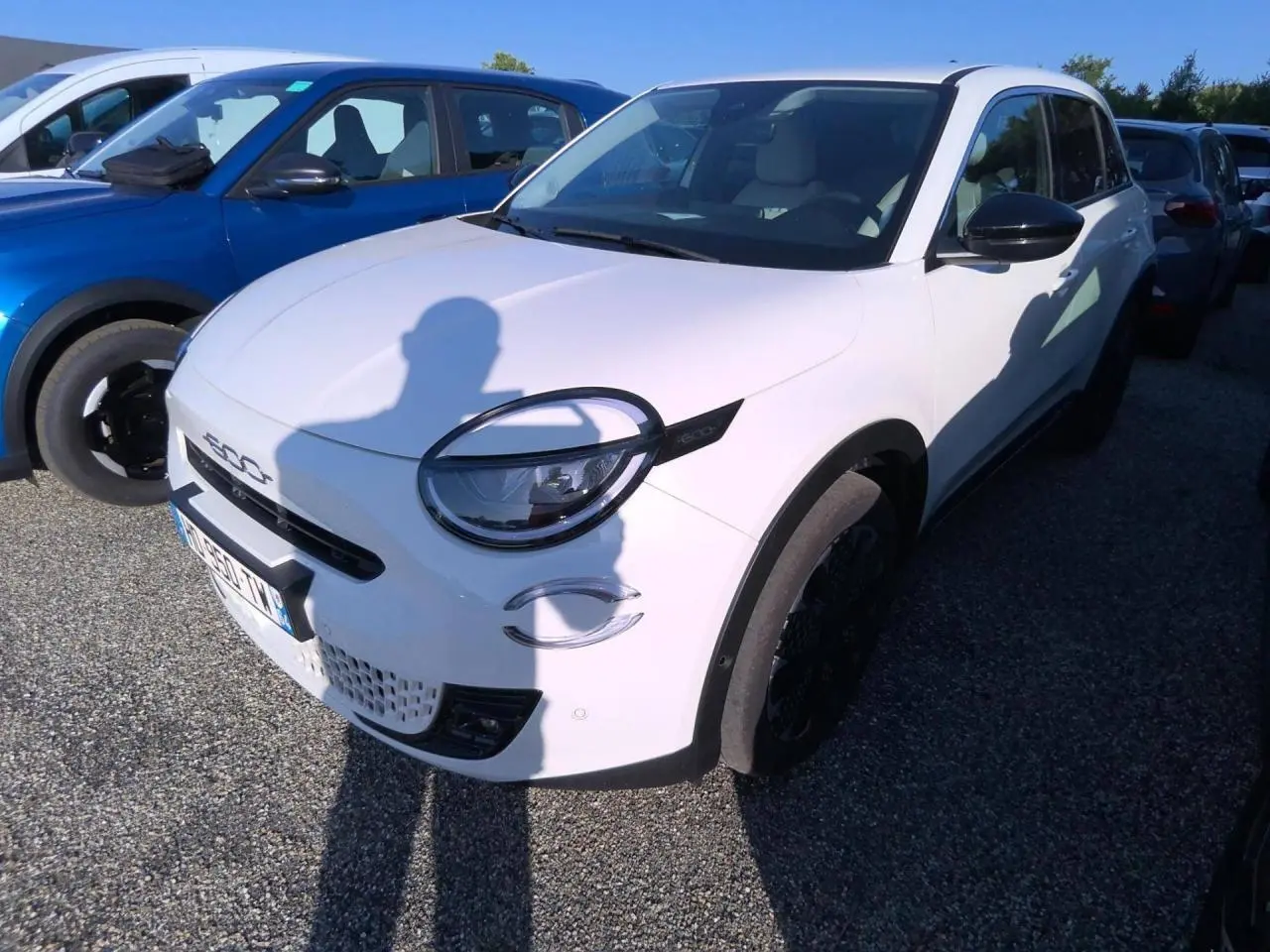 Vue 3/4 avant droit d'une FIAT 600 blanche 2025 avec phares ronds et détails noirs contrastants.