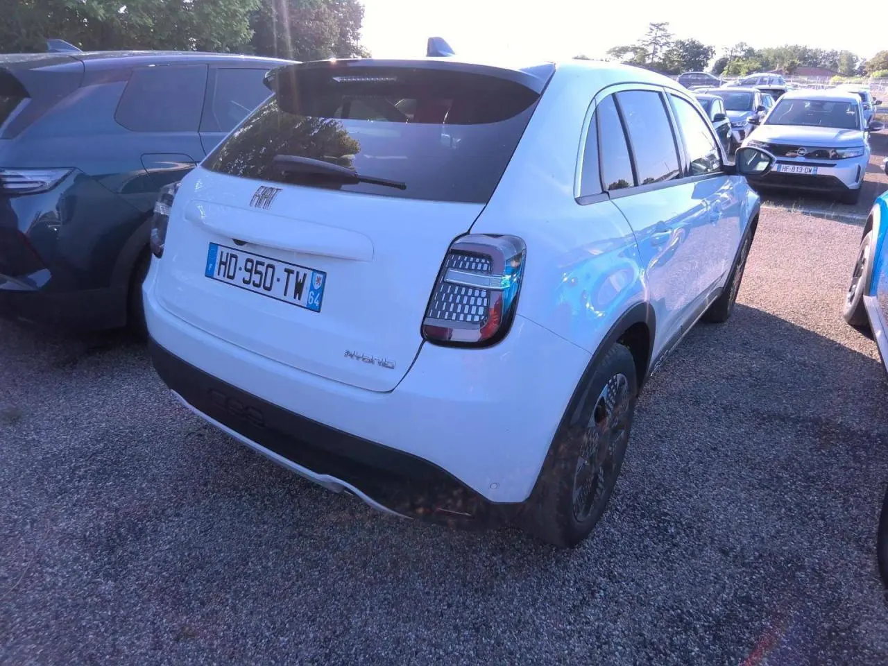 Vue 3/4 arrière droite d'une FIAT 600 blanche hybride 2025 avec feux arrière à motifs LED distinctifs.