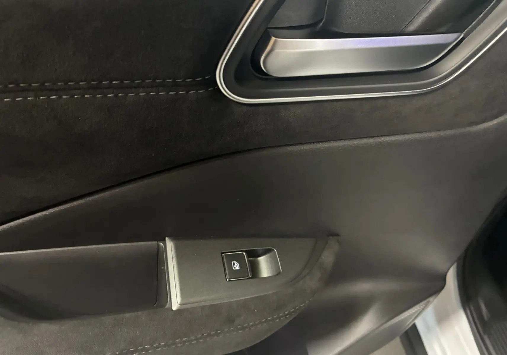 Gros plan sur la poignée intérieure et le bouton de lève-vitre côté conducteur du Nissan Qashqai blanc nacré 2025.