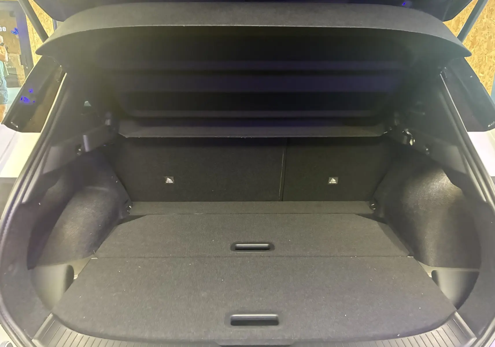 Coffre ouvert du Nissan Qashqai 2025 blanc nacré métal avec toit noir, montrant un espace de chargement spacieux et plat.