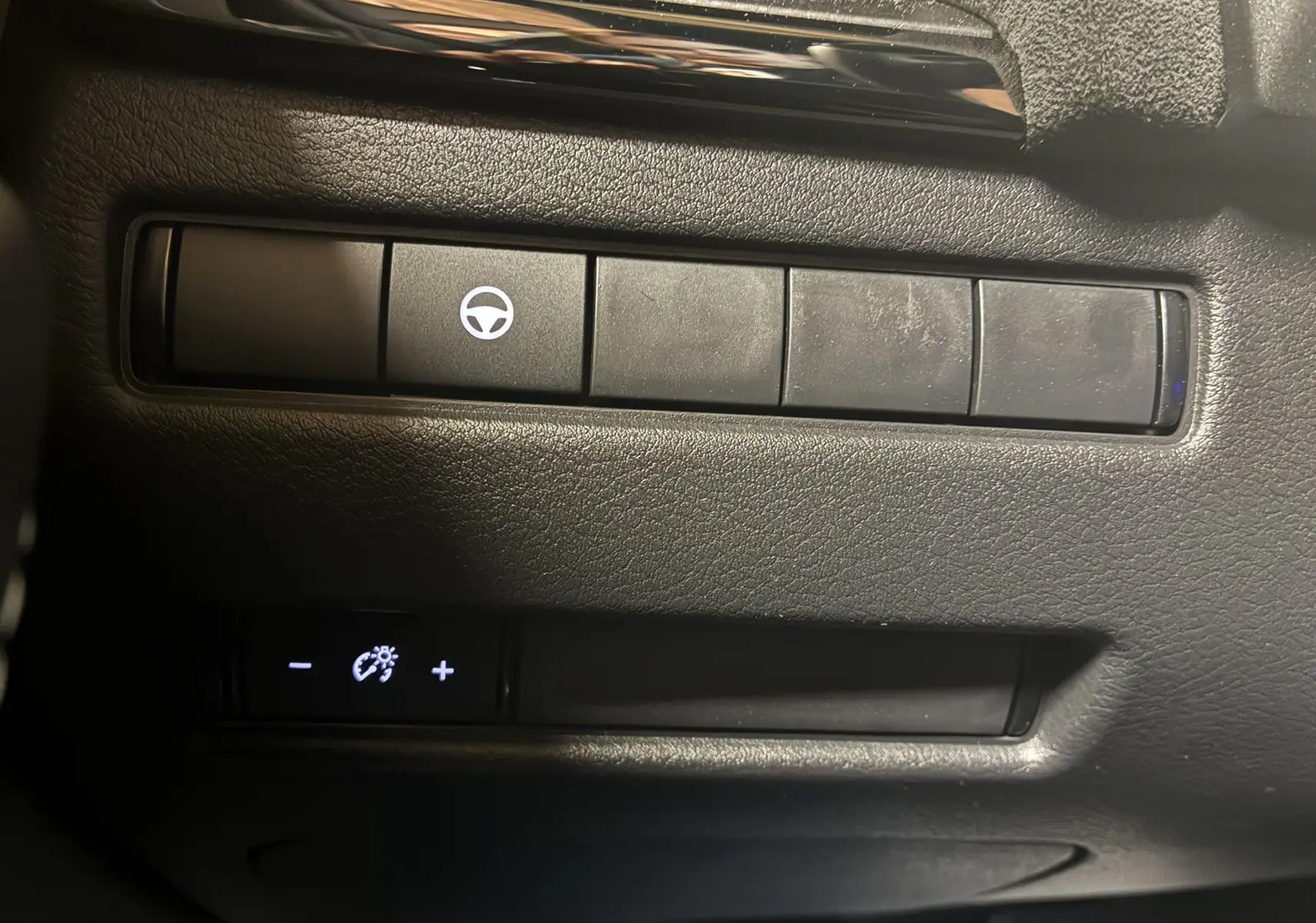 Boutons de commande du tableau de bord du Nissan Qashqai 2025, avec symbole de volant et réglage de luminosité.