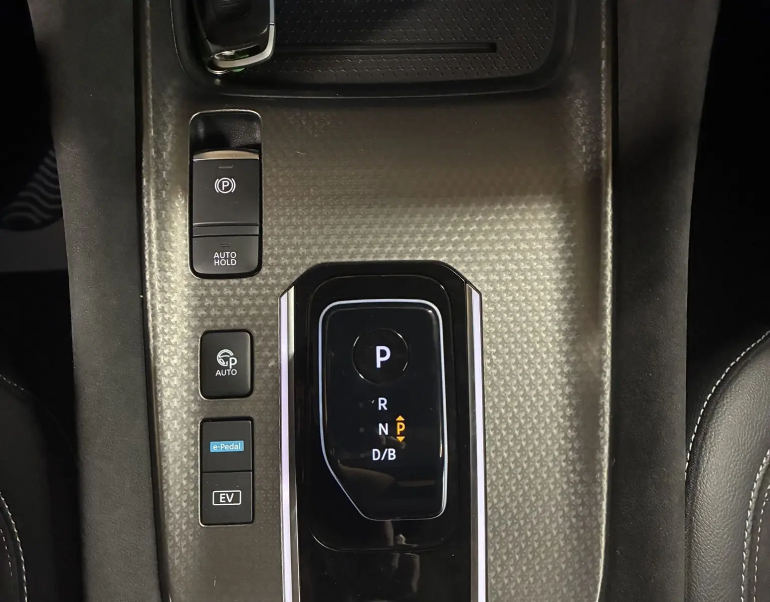Vue plongeante sur la console centrale noire du Nissan Qashqai blanc nacré, avec levier de vitesses automatique et clé posée.