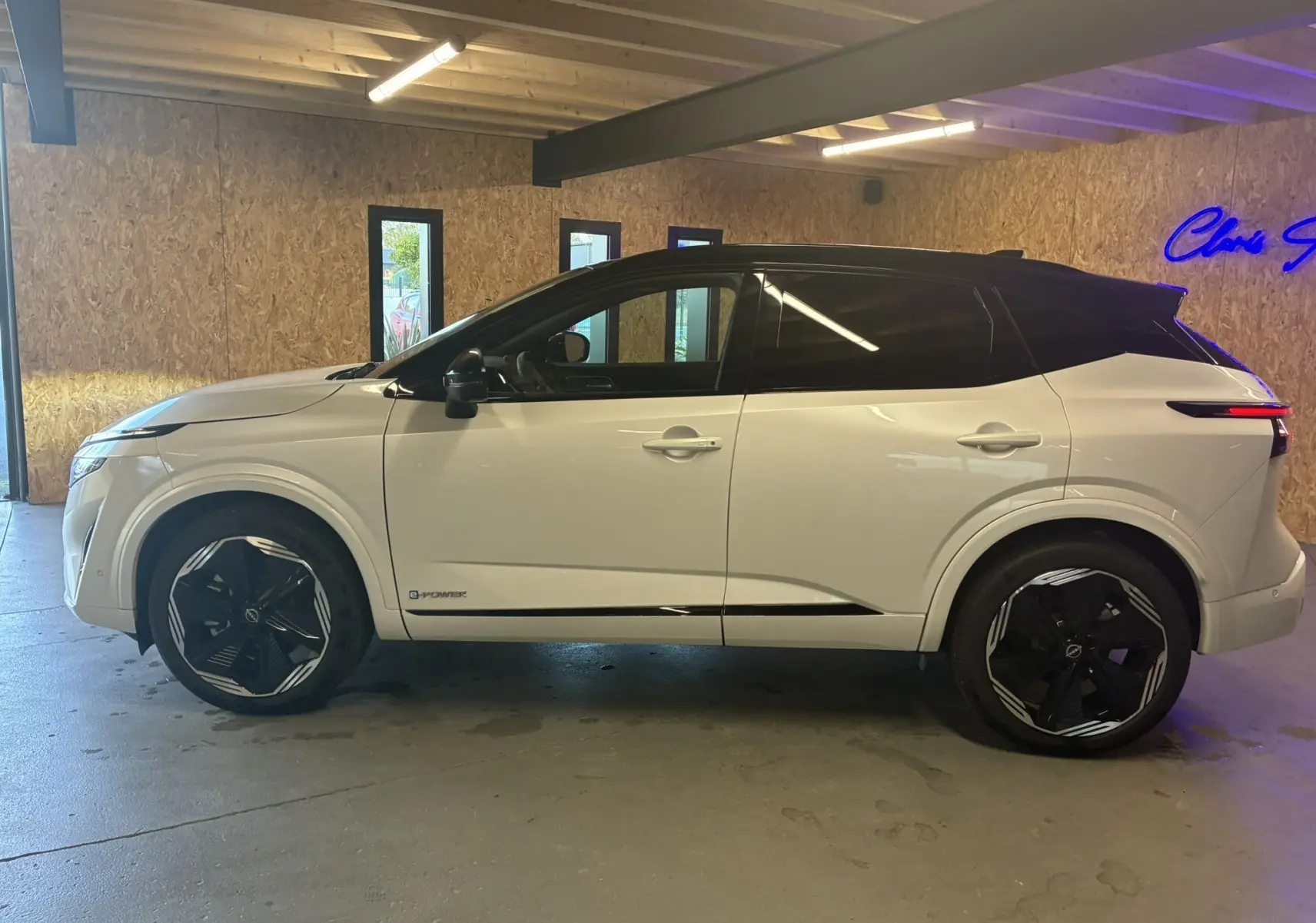 Vue latérale gauche du Nissan Qashqai 2025 blanc nacré avec toit noir et jantes noires au design moderne.