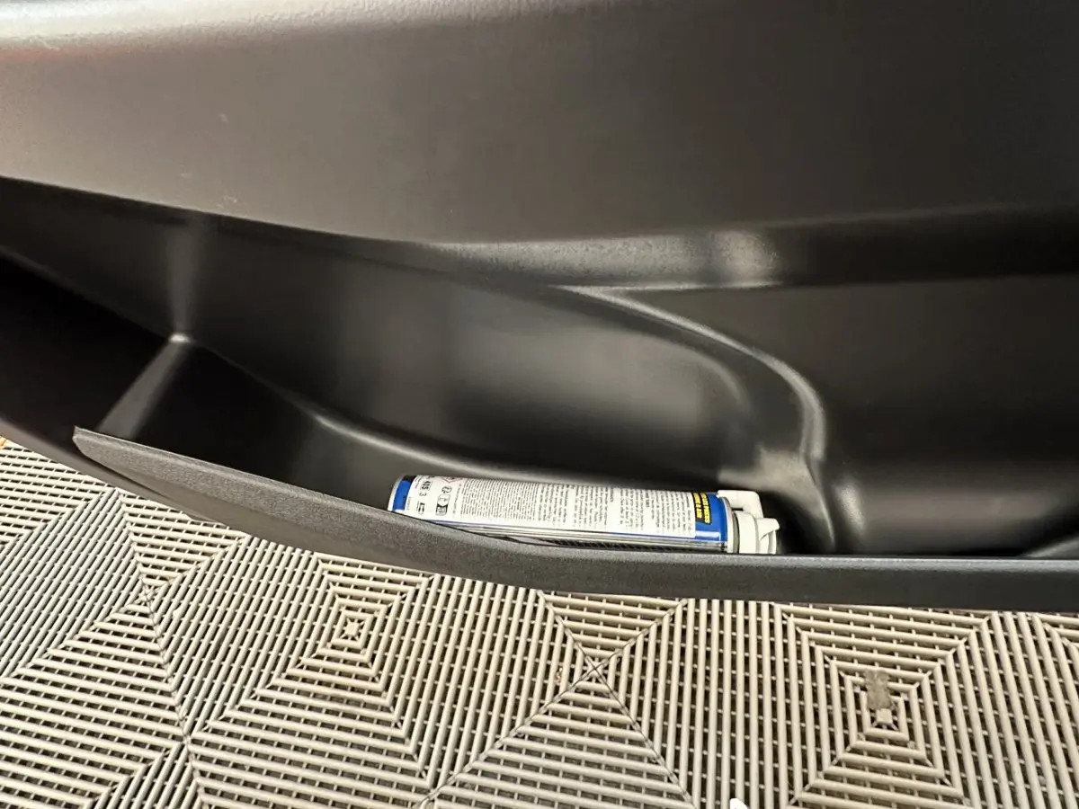 Rangement de porte intérieur noir avec un spray, sur une Aixam Ambition E City Pack blanc, vue côté conducteur.