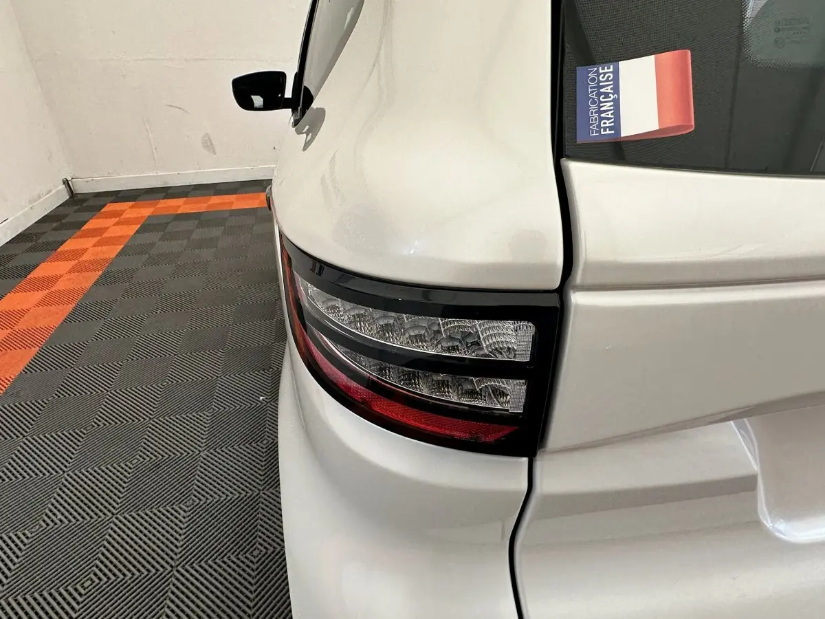 Gros plan sur le feu arrière droit blanc d'une Aixam Ambition E City Pack 2025 avec sticker "Fabrication Française" visible.