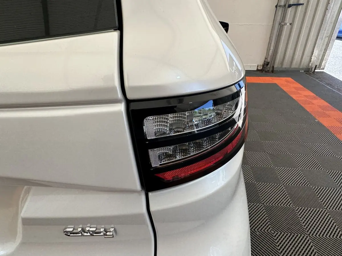 Gros plan sur le feu arrière droit blanc d'une Aixam Ambition E City Pack 2025, avec logo électrique visible.