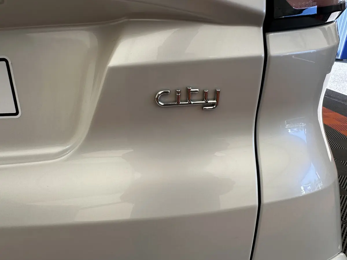 Gros plan sur l'arrière blanc d'une Aixam Ambition E City Pack 2025 avec l'insigne "city" visible sur le coffre.
