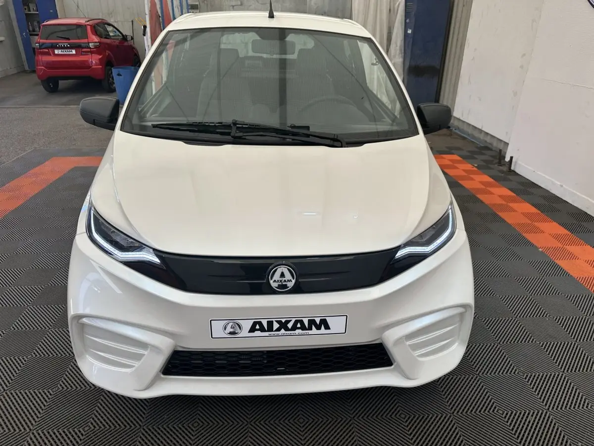 Vue frontale d'une Aixam Ambition E City Pack blanche 2025 avec calandre noire et phares LED distinctifs.
