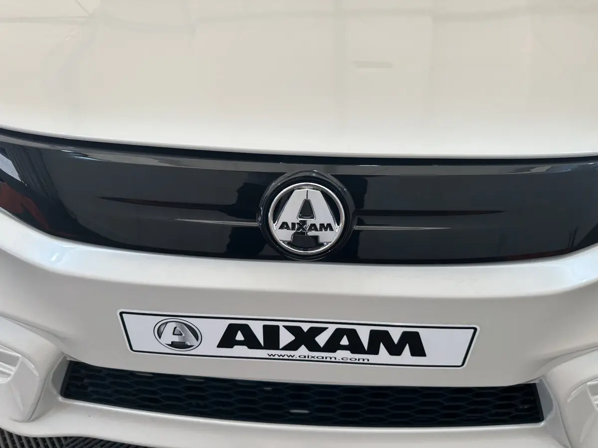Gros plan sur la calandre avant blanche de l'AIXAM AMBITION E CITY PACK 2025 avec logo et plaque distinctive.