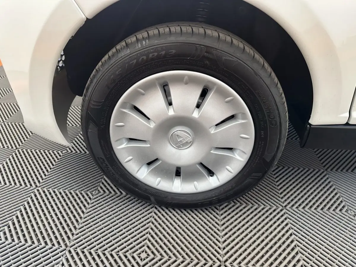 Gros plan sur la roue avant gauche blanche d'une Aixam Ambition E City Pack 2025 avec enjoliveur argenté.