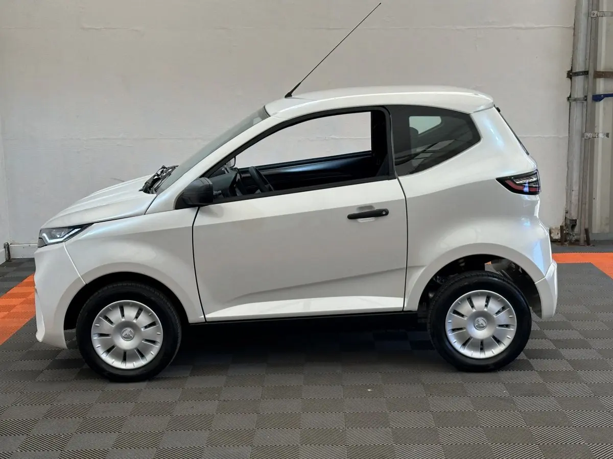 Vue de profil côté gauche de l'AIXAM AMBITION E CITY PACK 2025 blanc, petite citadine électrique compacte.