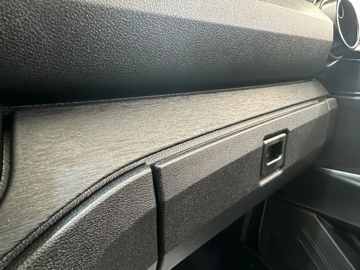 Gros plan sur la boîte à gants et la planche de bord noire texturée de l'AIXAM AMBITION E CITY PACK 2025.