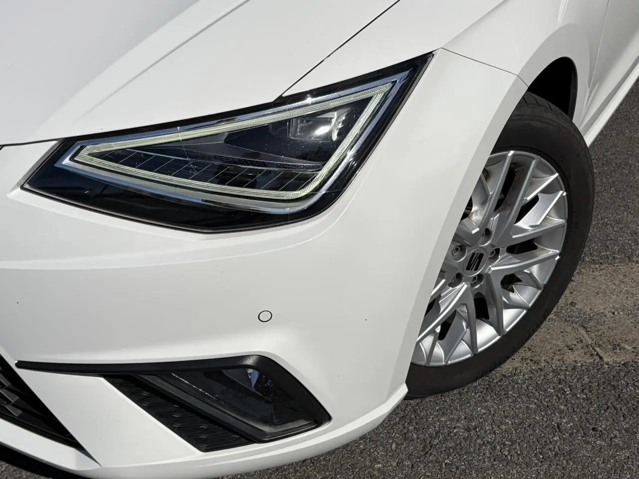 Gros plan sur l'avant droit blanc Candy de la SEAT IBIZA TSI 115 FR, mettant en valeur le phare LED et la jante alliage.