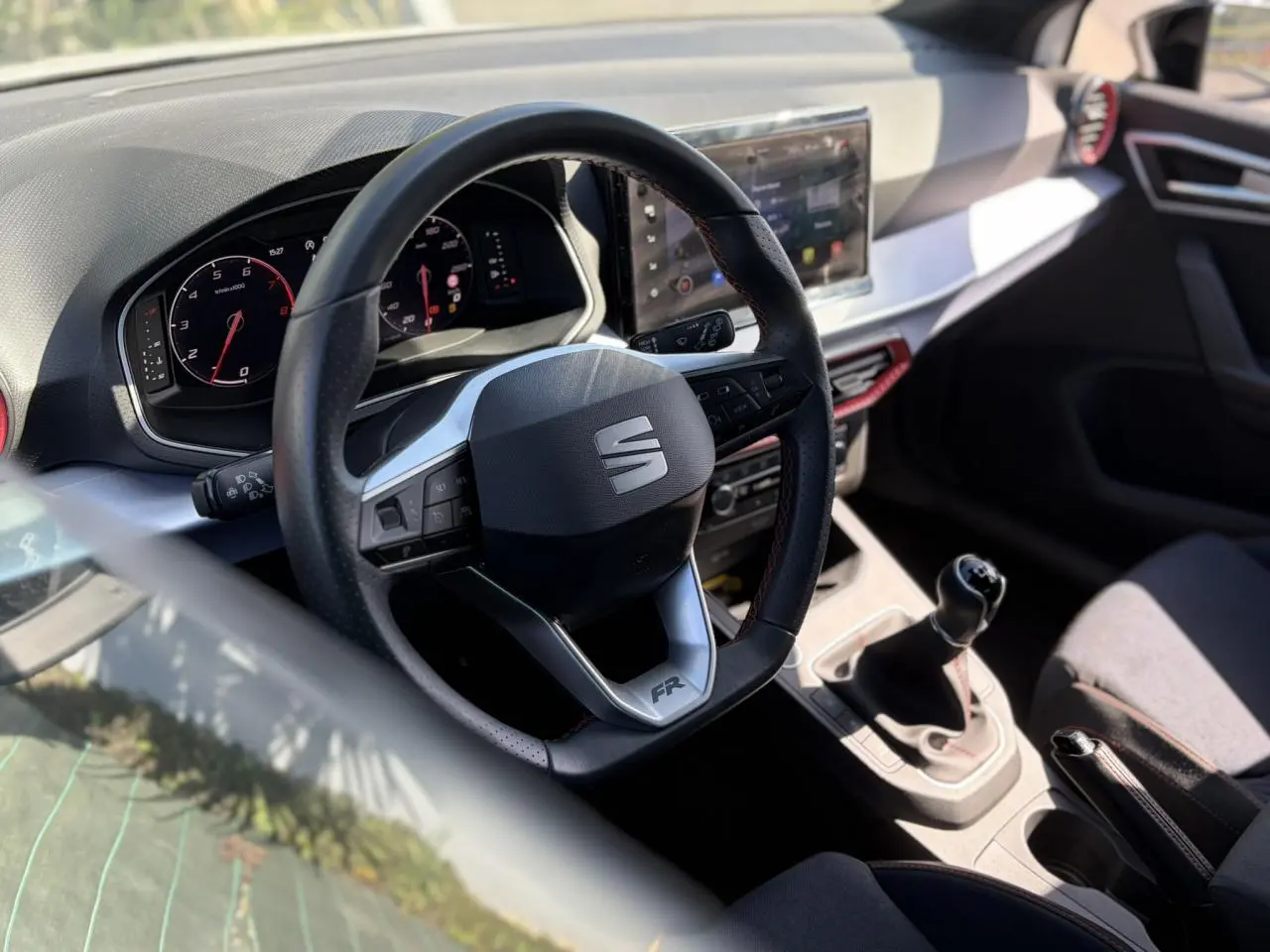 Vue intérieure centrée sur le volant FR et la console centrale avec levier de vitesse manuelle d'une SEAT Ibiza blanche.