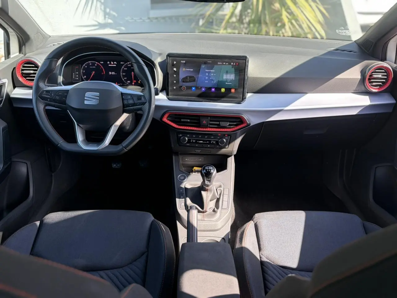 Intérieur SEAT Ibiza TSI 115 FR 2025 vu de face, tableau de bord avec écran tactile et détails rouges autour des aérateurs.