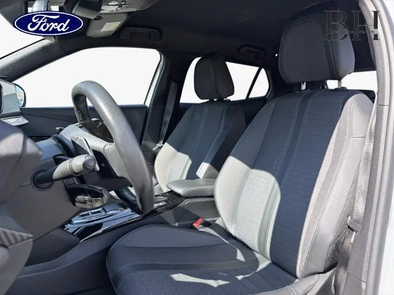 Intérieur avant côté conducteur du Peugeot 2008 2022, sièges tissu gris et volant multifonction visible.