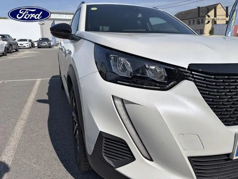 Vue avant gauche rapprochée du Peugeot 2008 blanc nacré 2022 avec phares LED et calandre noire distinctive.