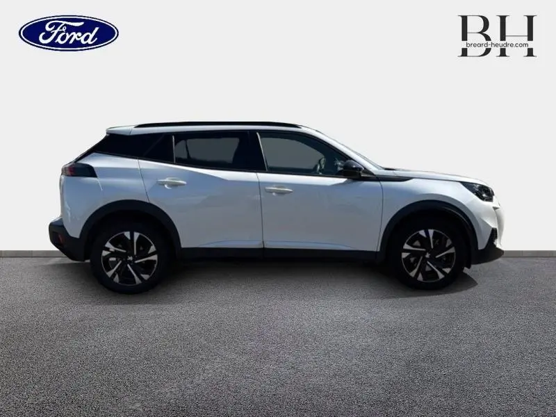 Peugeot 2008 blanc nacré en profil droit, avec jantes alu noires et toit noir contrasté visible.