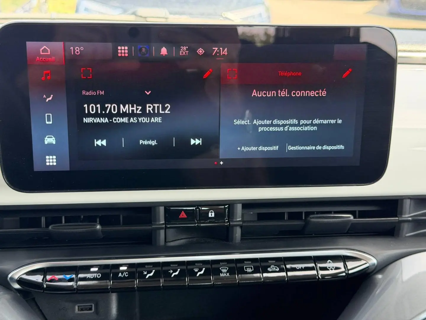 Vue rapprochée de l'écran tactile et de la console centrale de la Fiat 500 e blanche, affichant la radio et les commandes clim.