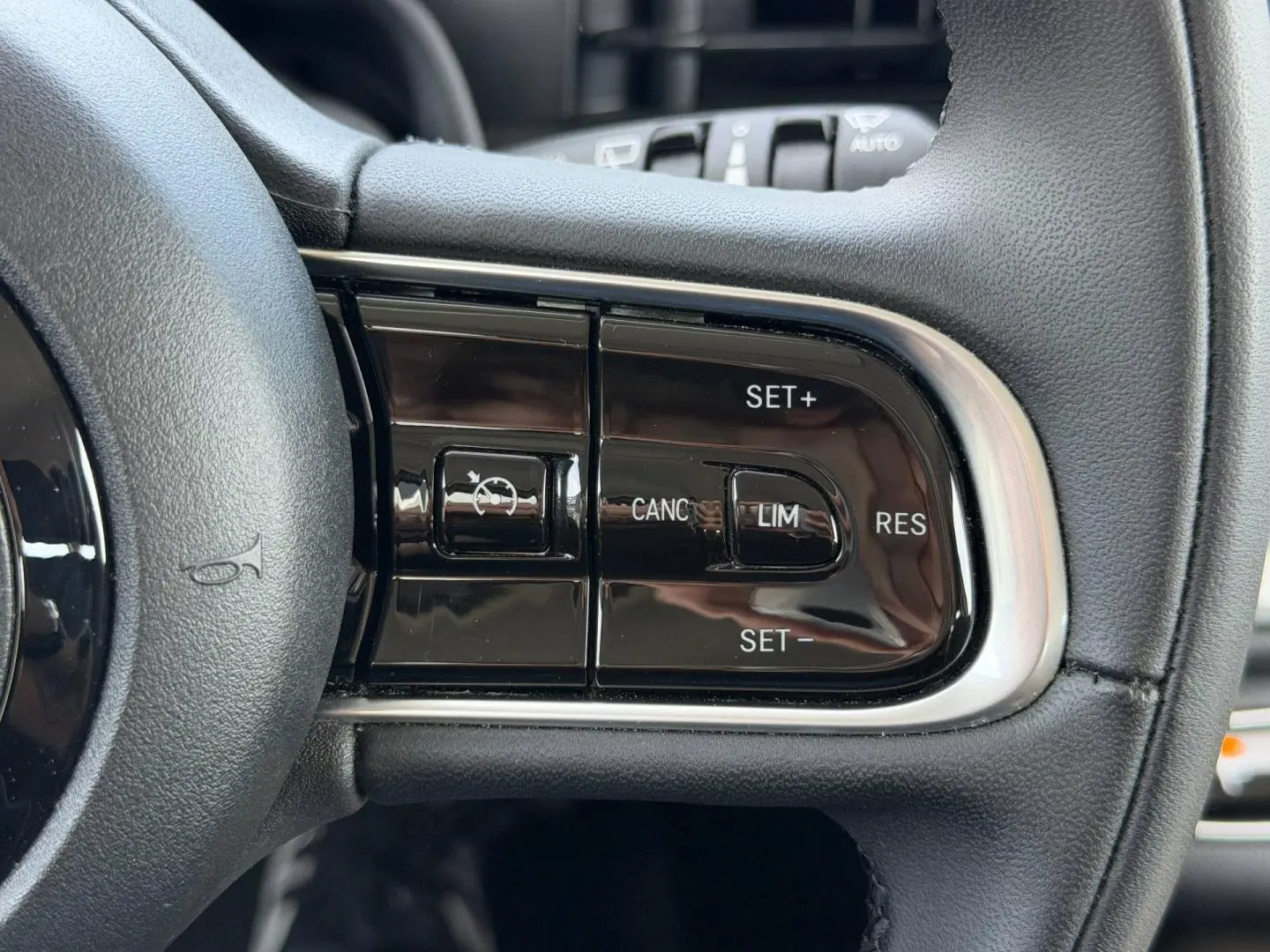 Gros plan sur les commandes du régulateur de vitesse au volant noir de la Fiat 500 électrique blanche 2023.