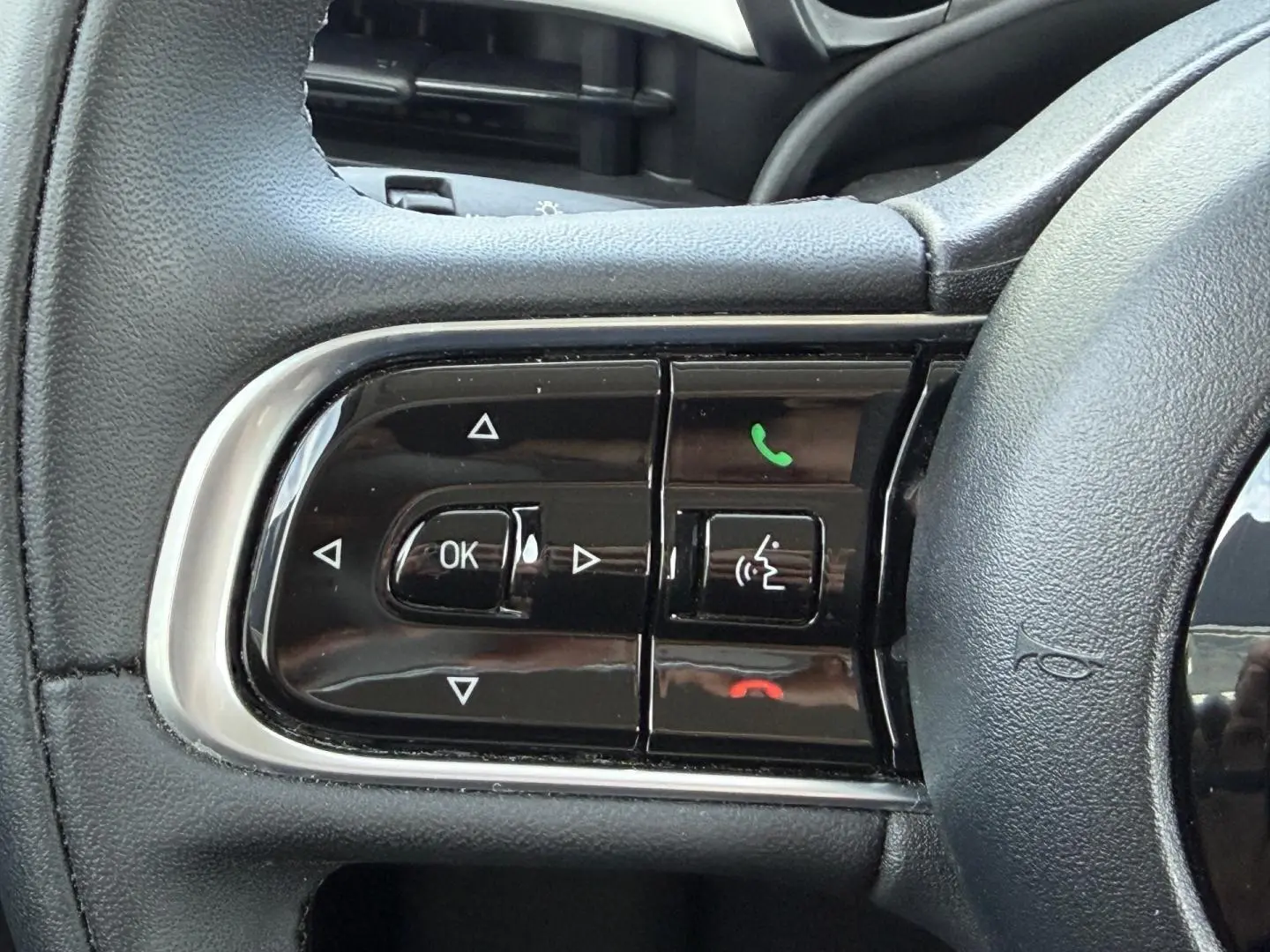 Gros plan sur les commandes multifonctions noires du volant de la Fiat 500 électrique blanche 2023.