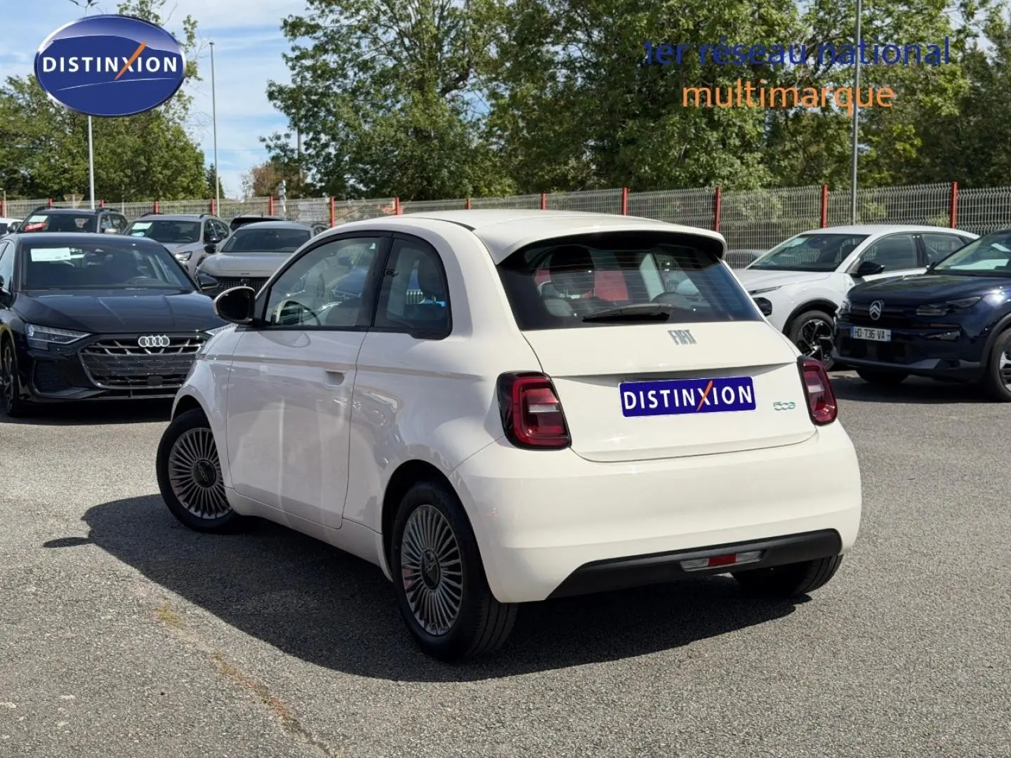 Vue 3/4 arrière droite d'une Fiat 500 électrique blanche 2023 avec feux arrière LED et becquet arrière.