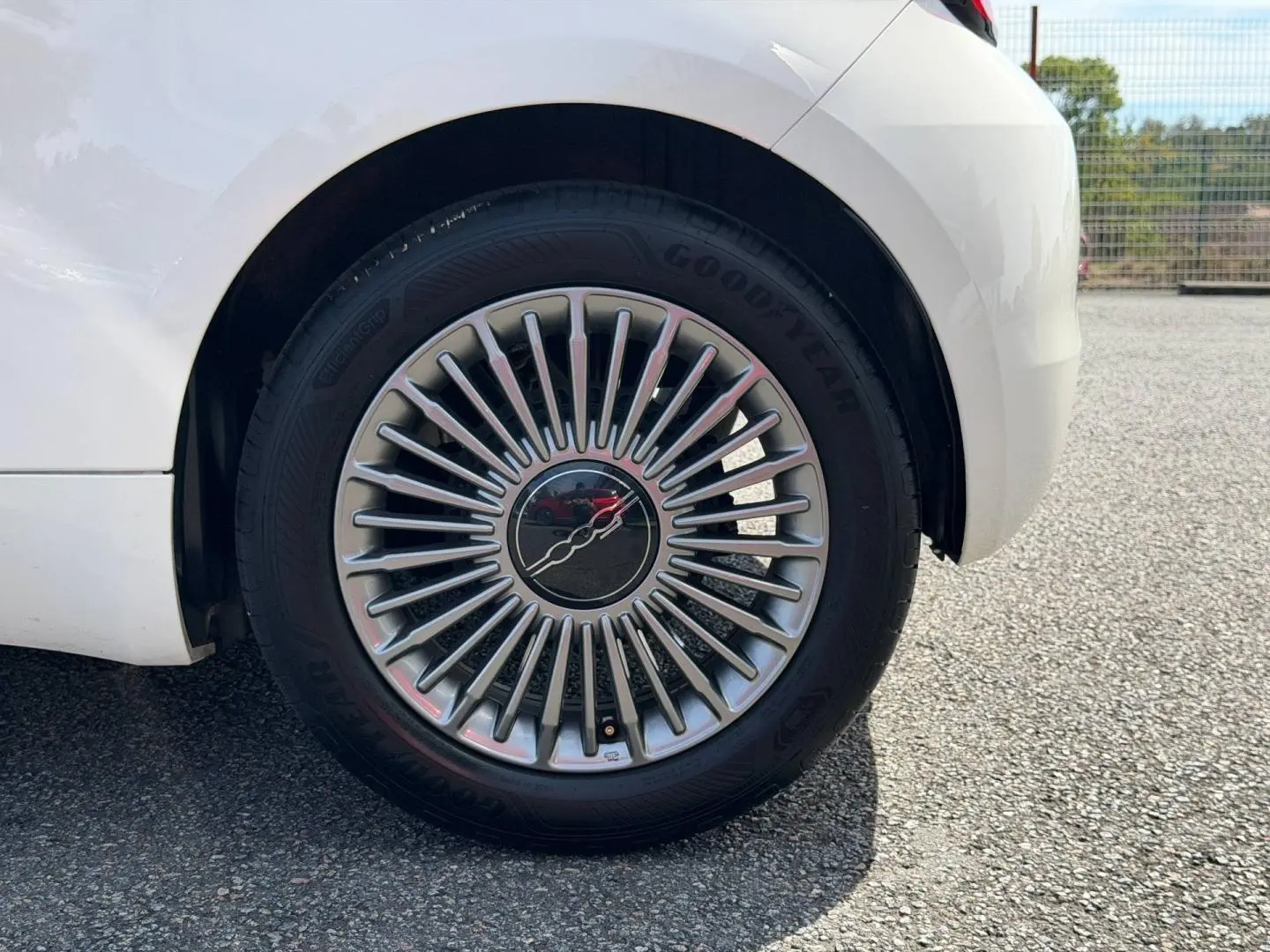 Gros plan sur la roue arrière droite blanche d'une Fiat 500 électrique 2023 avec jante à rayons fins argentés.