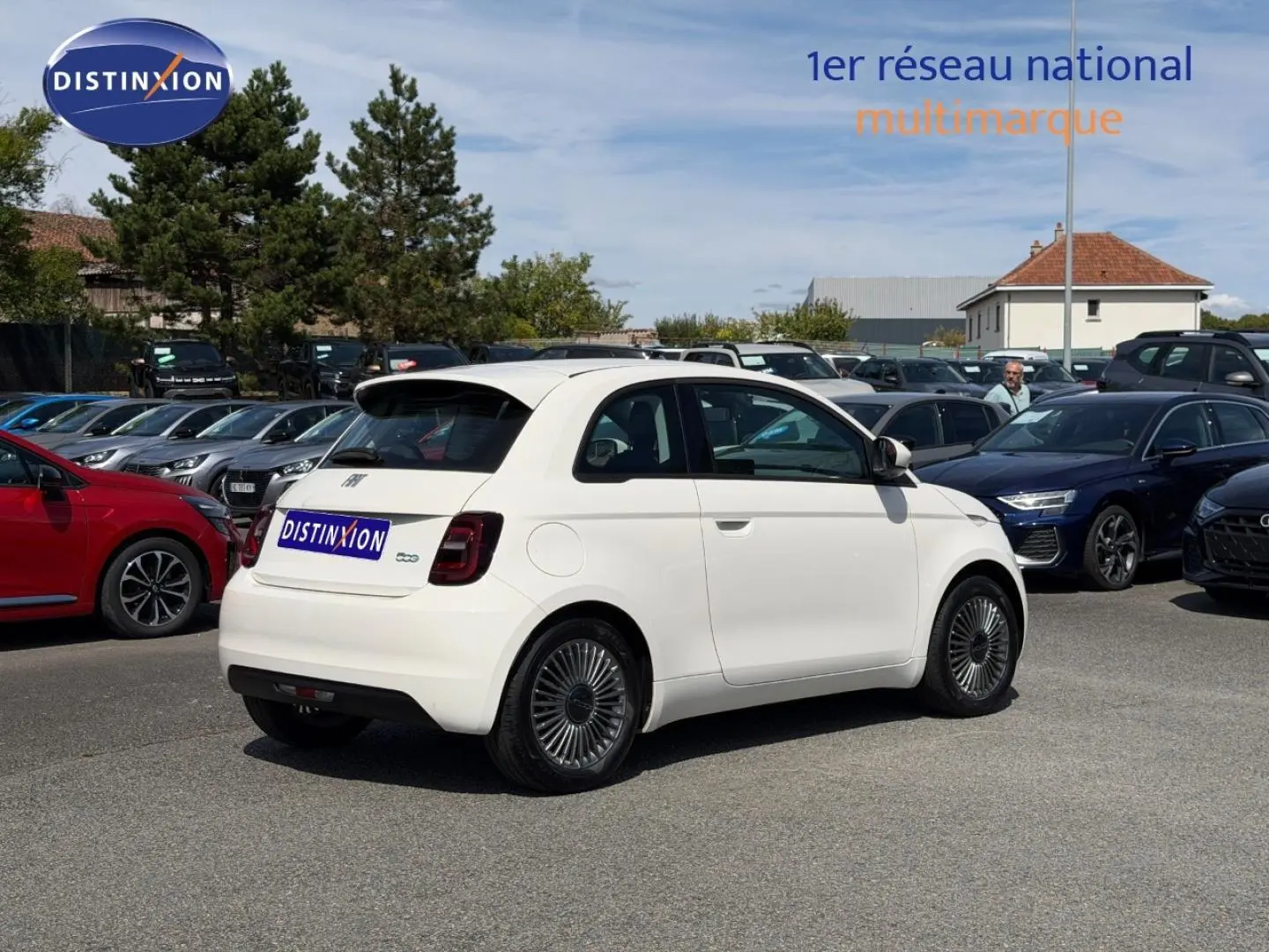 Vue 3/4 arrière droite d'une Fiat 500 électrique blanche 2023 avec jantes spécifiques et becquet arrière.