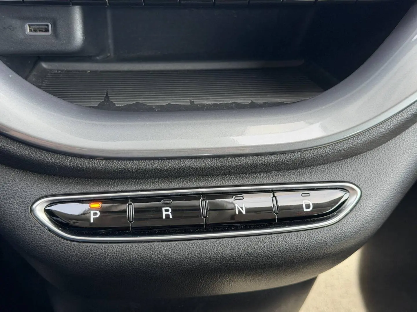 Gros plan sur la commande de boîte automatique noire avec indication orange sur "P" dans une Fiat 500 électrique blanche.