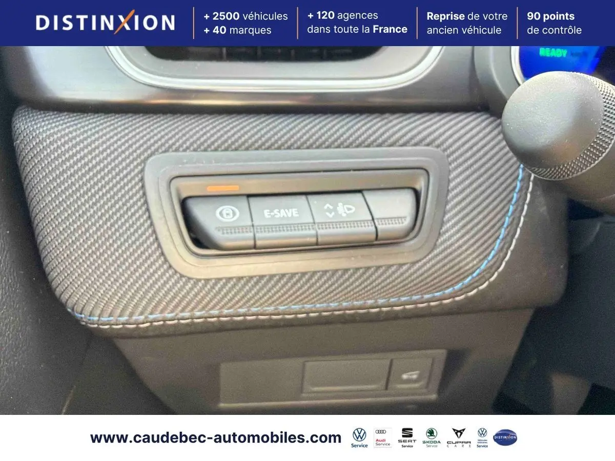 Gros plan sur les commandes E-Save et éclairage intégrées dans la console carbone avec surpiqûres bleues du Renault Symbioz gris.