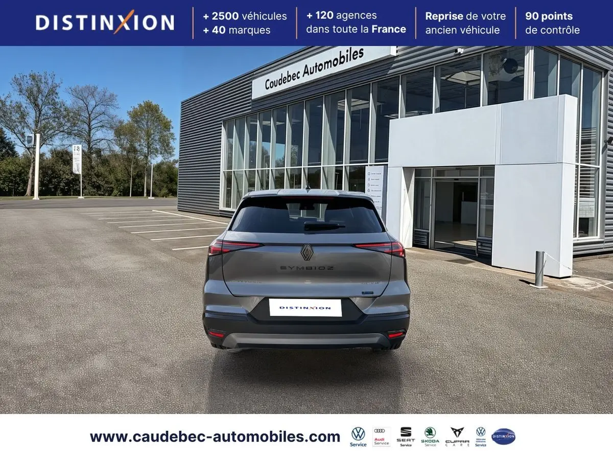 Vue arrière d’un Renault Symbioz gris métallisé garé devant un bâtiment moderne avec vitres larges.