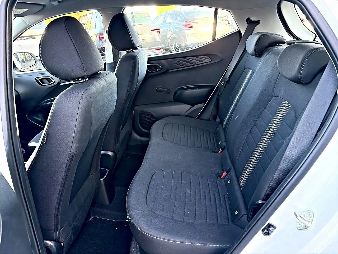 Vue intérieure côté droit sur la banquette arrière en tissu noir de la Hyundai i10 blanche 2024.