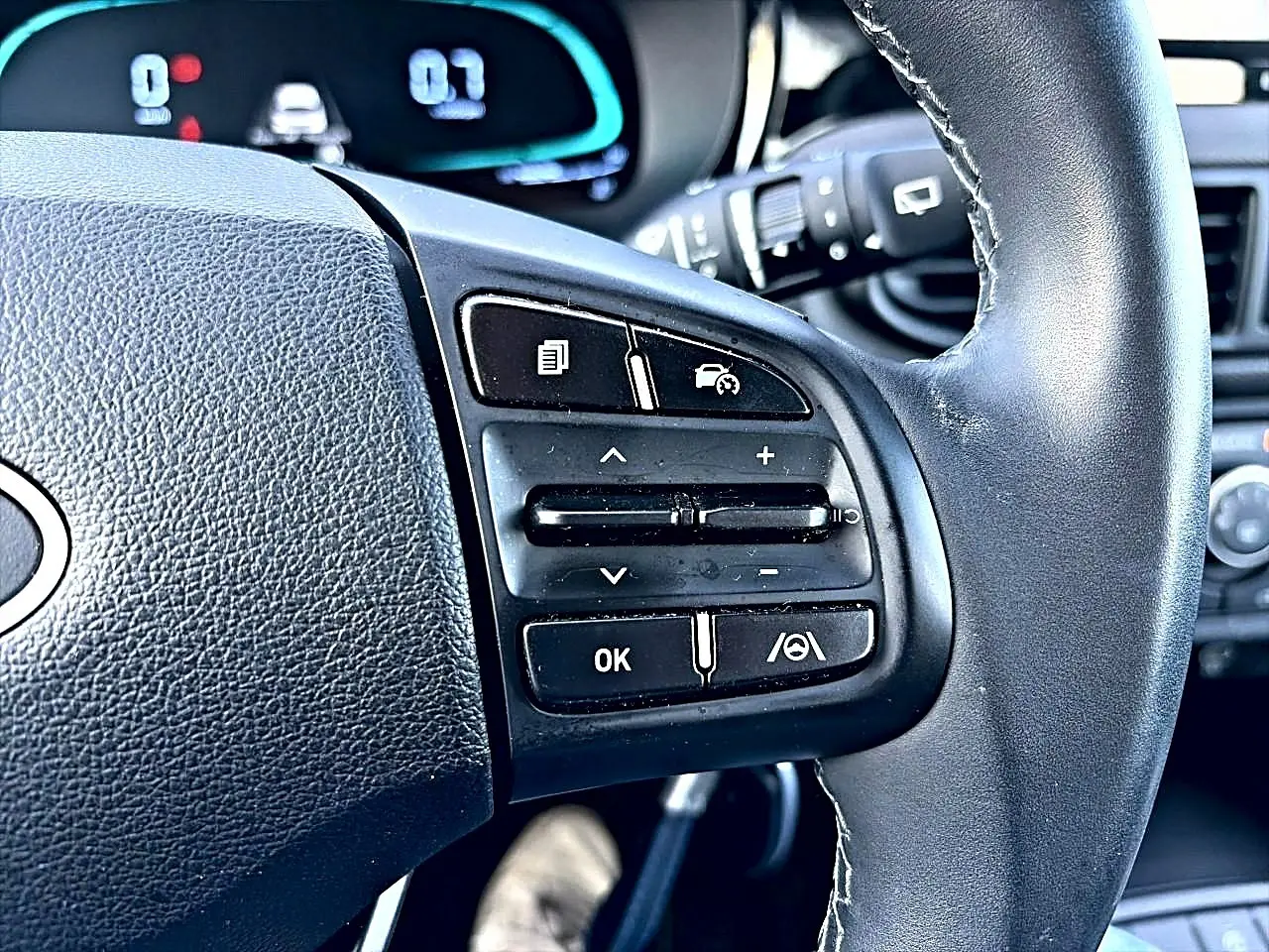 Gros plan sur les commandes multifonctions à droite du volant cuir noir d'une Hyundai i10 blanche de 2024.