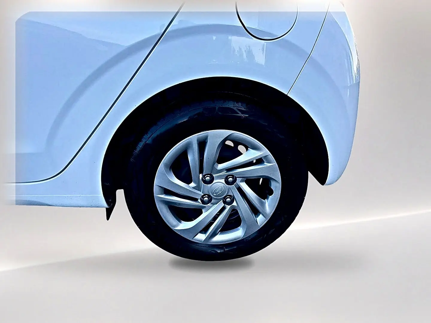 Gros plan sur la roue arrière droite d'une Hyundai i10 blanche avec jante alliage et passage de roue arrondi.