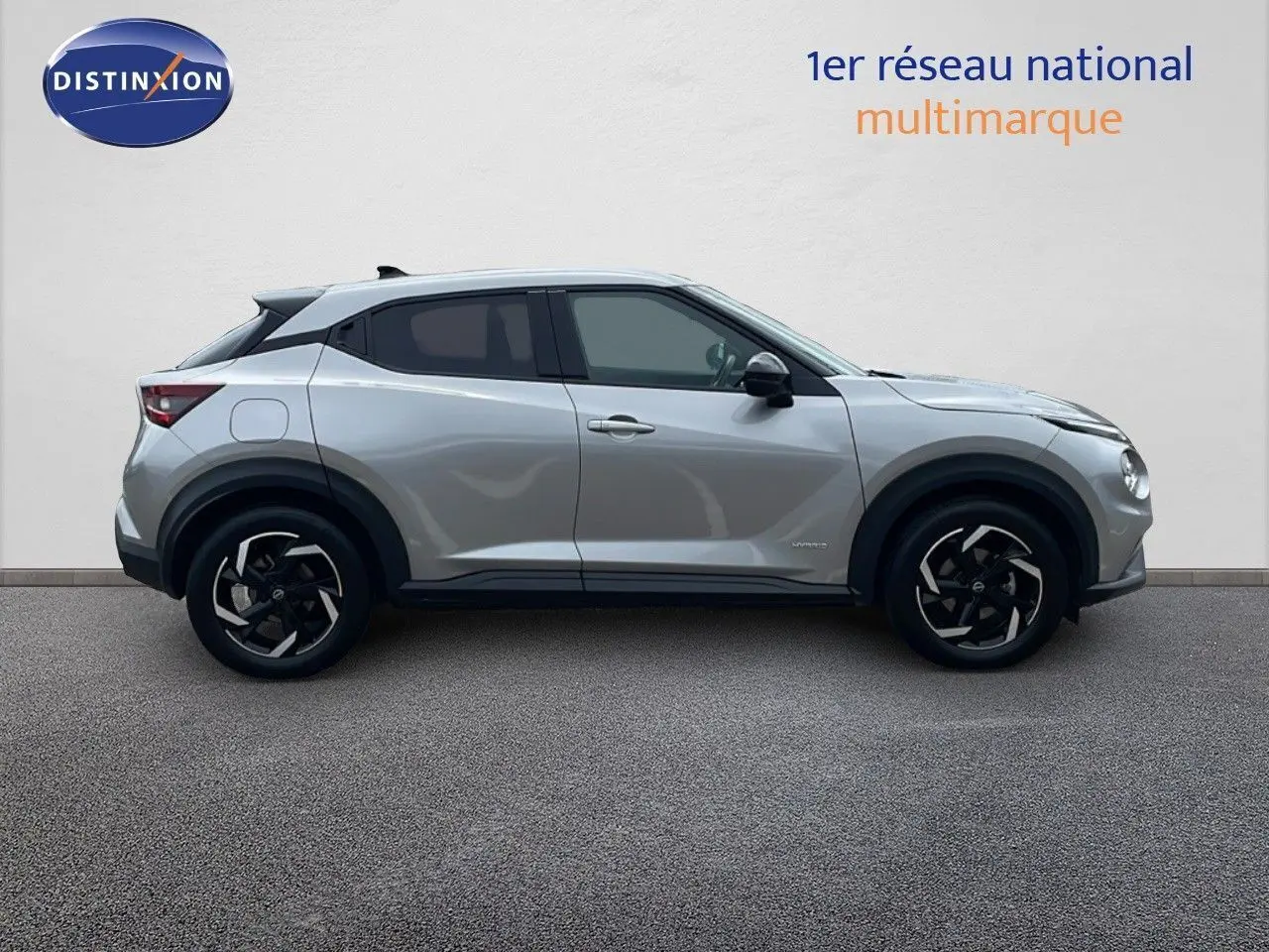 Profil droit d'un Nissan Juke Hybrid 143ch Business+ gris perle métal avec jantes noires et détails modernes.