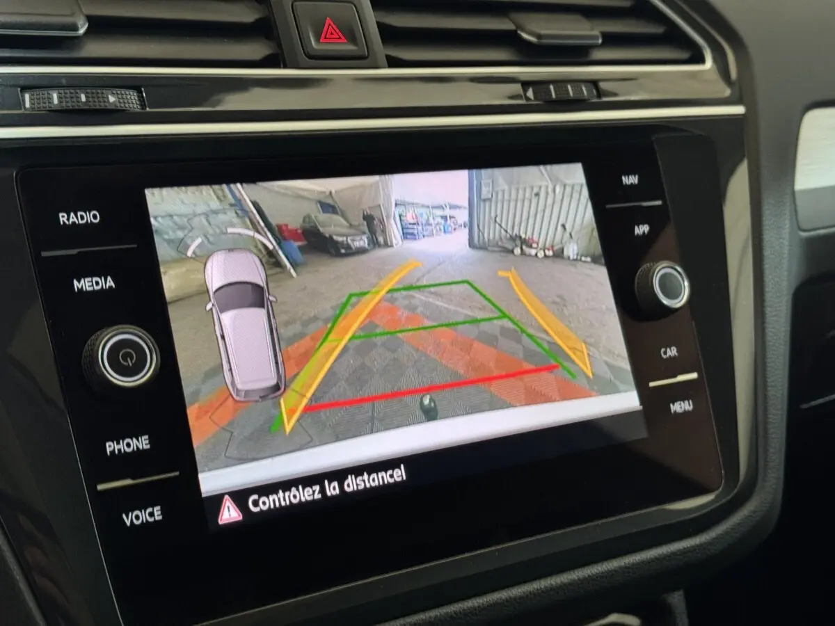 Écran tactile intérieur du Volkswagen Tiguan blanc montrant la caméra de recul avec guidage de trajectoire coloré.