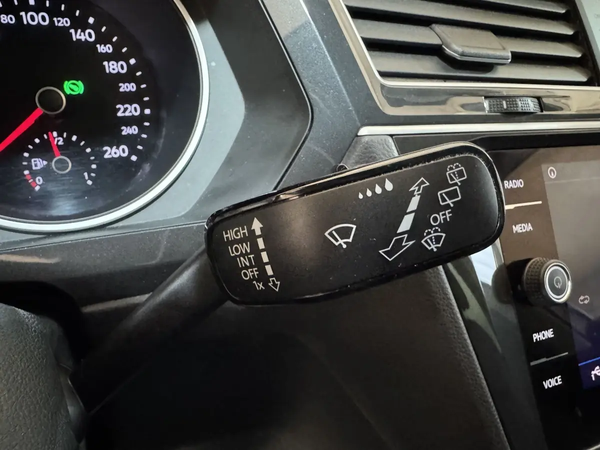 Gros plan sur la commande des essuie-glaces du Volkswagen Tiguan 2020, tableau de bord noir et écran tactile visible.