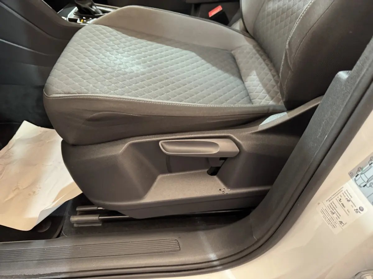 Gros plan sur le siège avant droit gris à motifs du Volkswagen Tiguan blanc, avec réglage manuel visible.