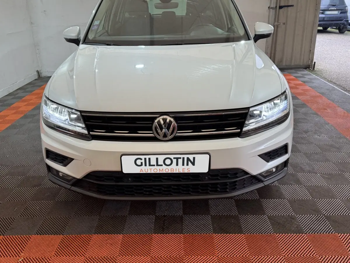 Vue frontale d'un Volkswagen Tiguan blanc 2020 avec phares LED allumés et calandre noire brillante.
