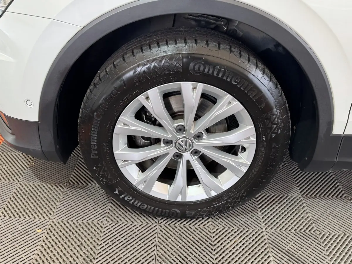 Gros plan sur la roue avant droite du Volkswagen Tiguan blanc, avec jante alliage argentée et pneu Continental.